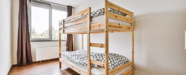 A pine bunk bed in a bright bedroom